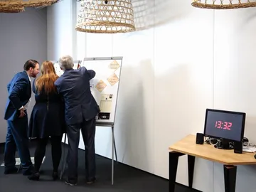 Vier Personen betrachten ein Flipchart in einem Besprechungsraum.