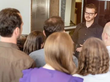 Man talking to a group of people in a modern room.