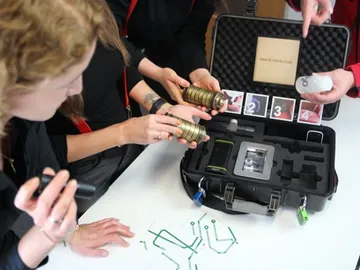 People explore a suitcase with mysterious objects.