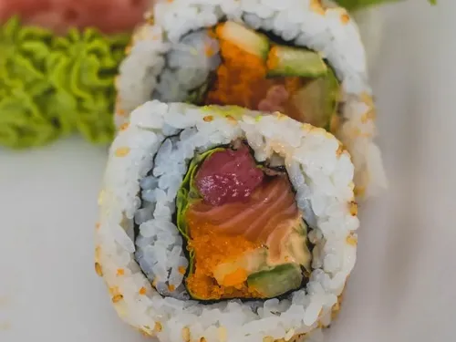 Sushi rolls are laid out on a white plate, appetizingly served.