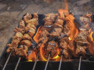 Spieße grillen über offenen Flammen in einem Grill.