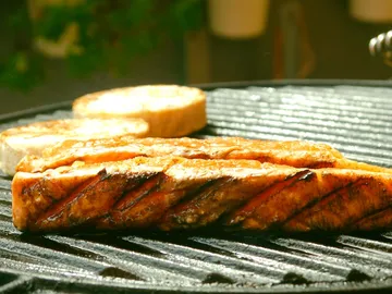 Grilled fish fry on a grill rack; close to toasted bread.