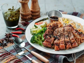 Grilled meat with vegetables and rice on a plate.