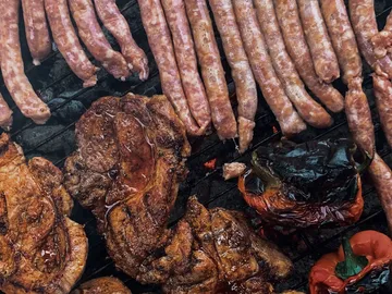 Grilled meat and sausages on grill, smoky environment.