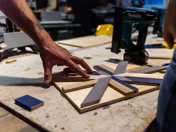 Hand berührt Holzteile auf dem Tisch in Werkstatt.