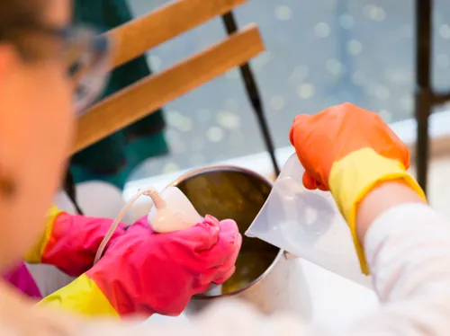 A person with gloves mixes liquid in a pot.