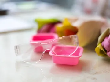 Glasses lie in pink containers on a table.