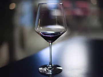 Weinglas mit rotem Wein steht auf einem Tisch.