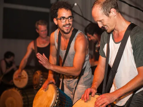 Trommler spielen rhythmisch im dunklen, festlichen Raum.