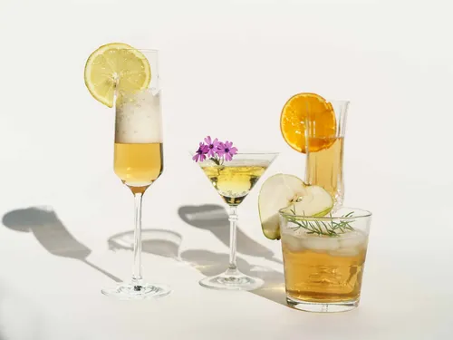 Different cocktails stand next to each other on a white background.