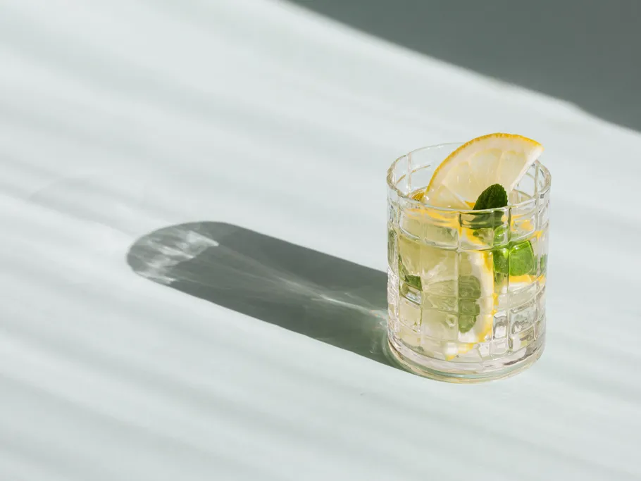 A glass with lemons and mint stands on a surface.
