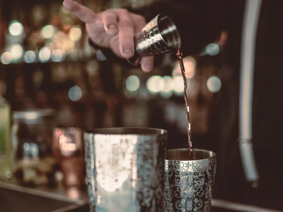 A bartender pours liquid out of a measuring cup.