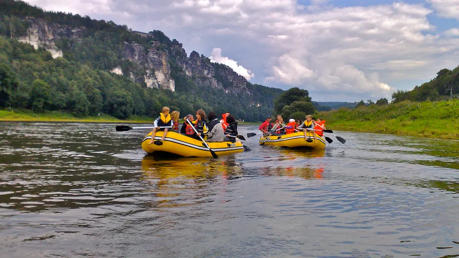 Two yellow boats are paddling on a quiet river.