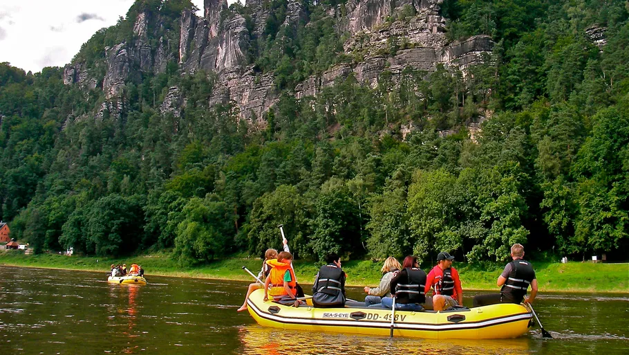 Gummiboot fährt ruhig auf einem Fluss, umgeben von Felsen.