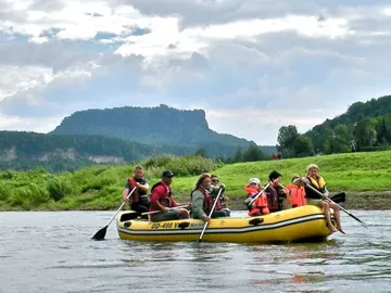 Yellow boat with people paddling on a river.