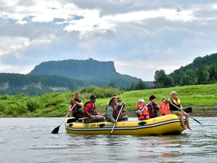 Gelbes Boot mit Personen paddelt auf einem Fluss.