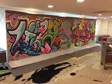 Graffiti-Wand mit bunten Schriftzügen in einem Innenraum.