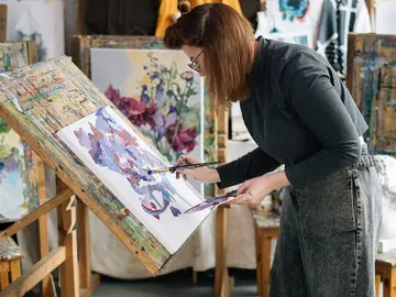 An artist paints colorfully on a canvas in the studio.