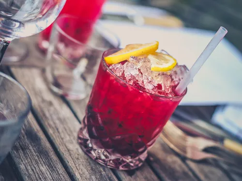 Colorful cocktail with ice and lemon slices on table.