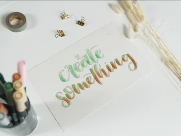 Bunt beschriftetes Papier liegt auf einem Tisch mit Stiften.