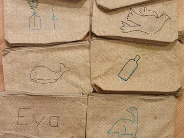 Six cloth bags with colorful embroideries on burlap.