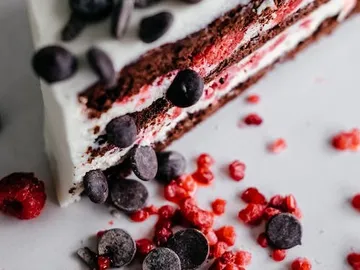 Cake with chocolate and berries, placed on white surface.
