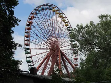 Riesenrad dreht sich sanft in einem Park mit Bäumen.