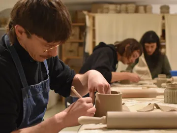 Pottery work in a workshop, several people work concentrated.