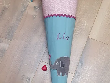 Schultüte mit Elefant und Name. Liegt auf dem Boden.