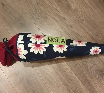Sugar bag with floral patterns is lying on wooden floor.