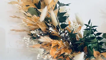 Ein Kranz aus Trockenblumen hängt an der Wand.