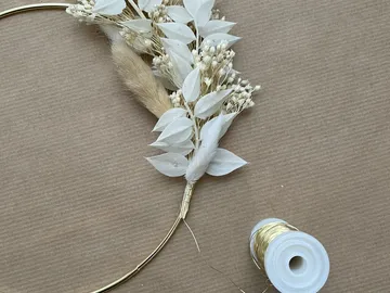 Kreisförmiger Kranz mit getrockneten weißen Blumen, auf Karton.