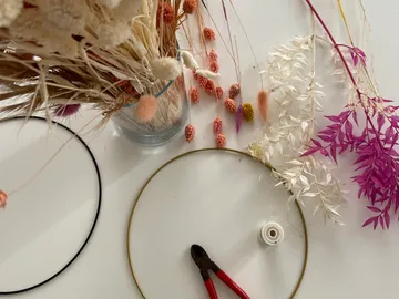 Trockenblumen und Werkzeuge zum Basteln auf dem Tisch.