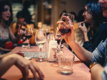 Women drink wine and talk at a table.