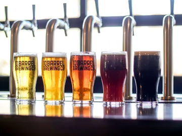 Five beer glasses stand side by side at a bar counter.