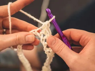 Wool is worked with a purple crochet hook.