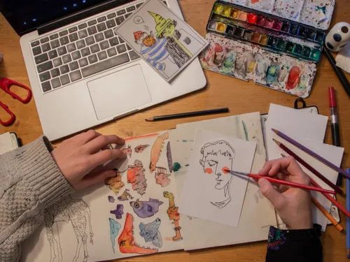 Sketchbook shows drawings, coloring hands with pens.