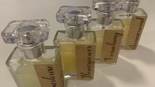 Four perfume bottles stand side by side on a table.