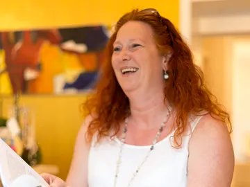 Smiling woman holding a book in colorful room.