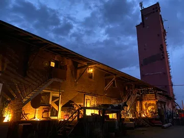 Old warehouse with illuminated courtyard at dusk.