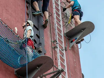 Climbers use a wall with outdoor safety equipment.