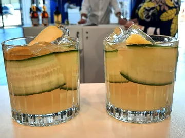 Two glasses of drink filled with ice and pickles.