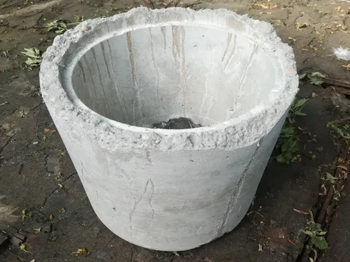 The concrete container is empty on the ground, surrounded by soil.