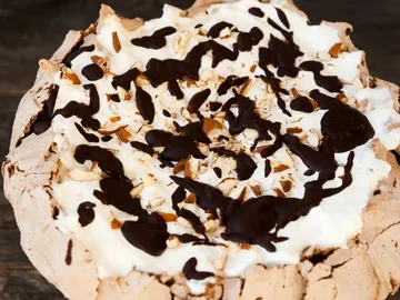 Chocolate cake with cream and nuts on a wooden background.