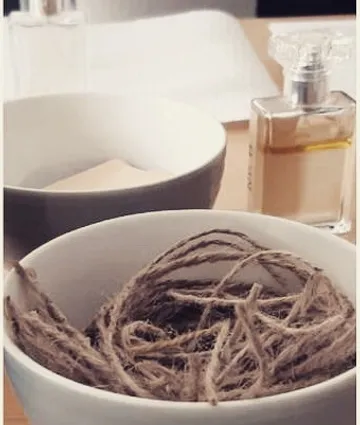 Zwei Schalen mit Garn und Parfüm auf einem Tisch.