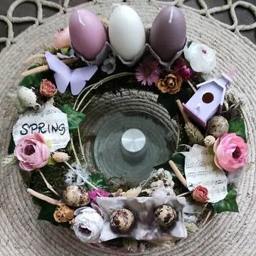 Ein dekorativer Kranz mit bunten Eiern und Blumen.