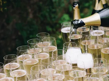 Champagner wird in Gläser im Grünen gegossen.