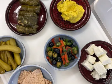 Verschiedene Gerichte auf Tellern: Salat, Käse, Oliven, Dips.