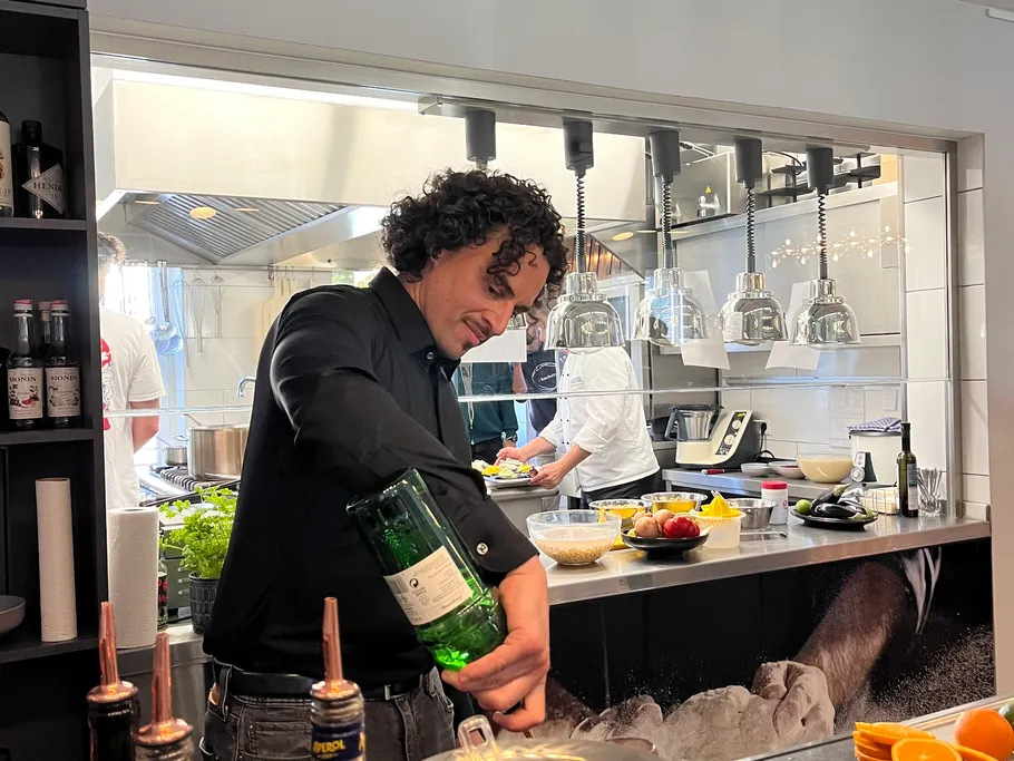 A man pours a liquid into a bottle in a kitchen.
