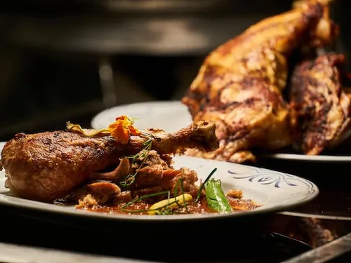 Gegrilltes Huhn auf einem Teller, mit Beilagen serviert.